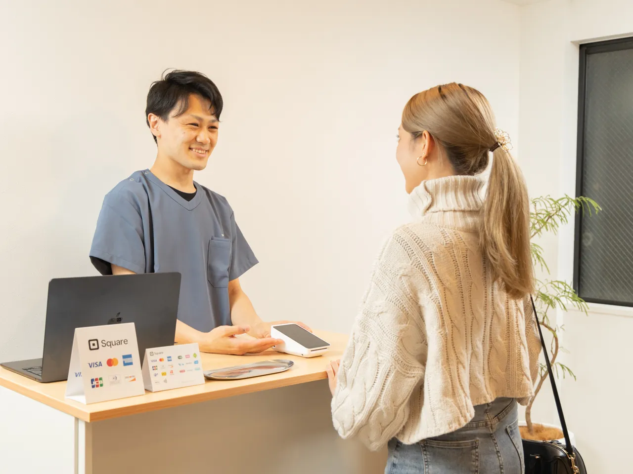 鍼灸整体院の受付カウンターでのお会計と次回予約案内の様子